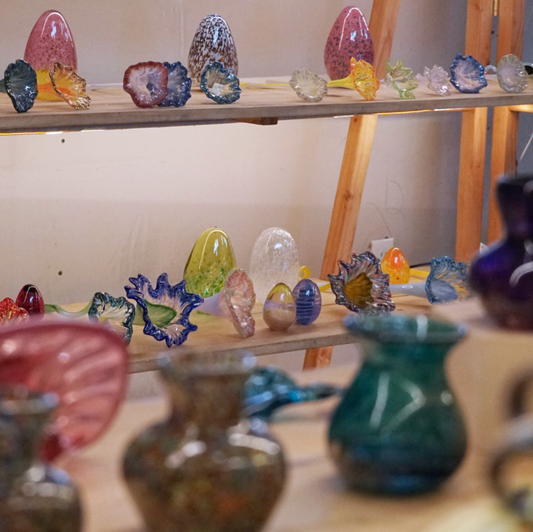 glass flowers, eggs, and vases on our gallery shelves